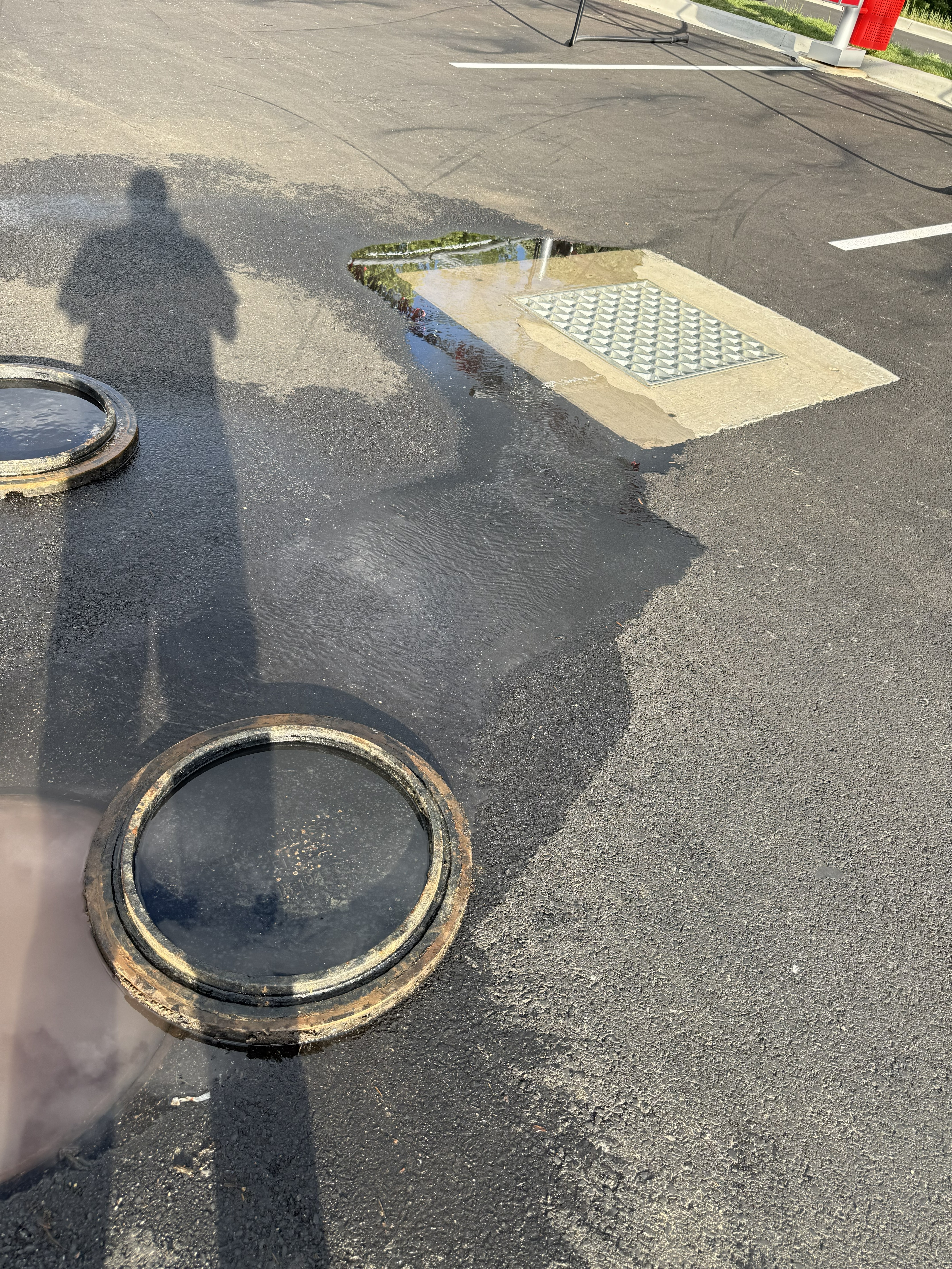 Multiple parking lot drain covers removed showing flooded system