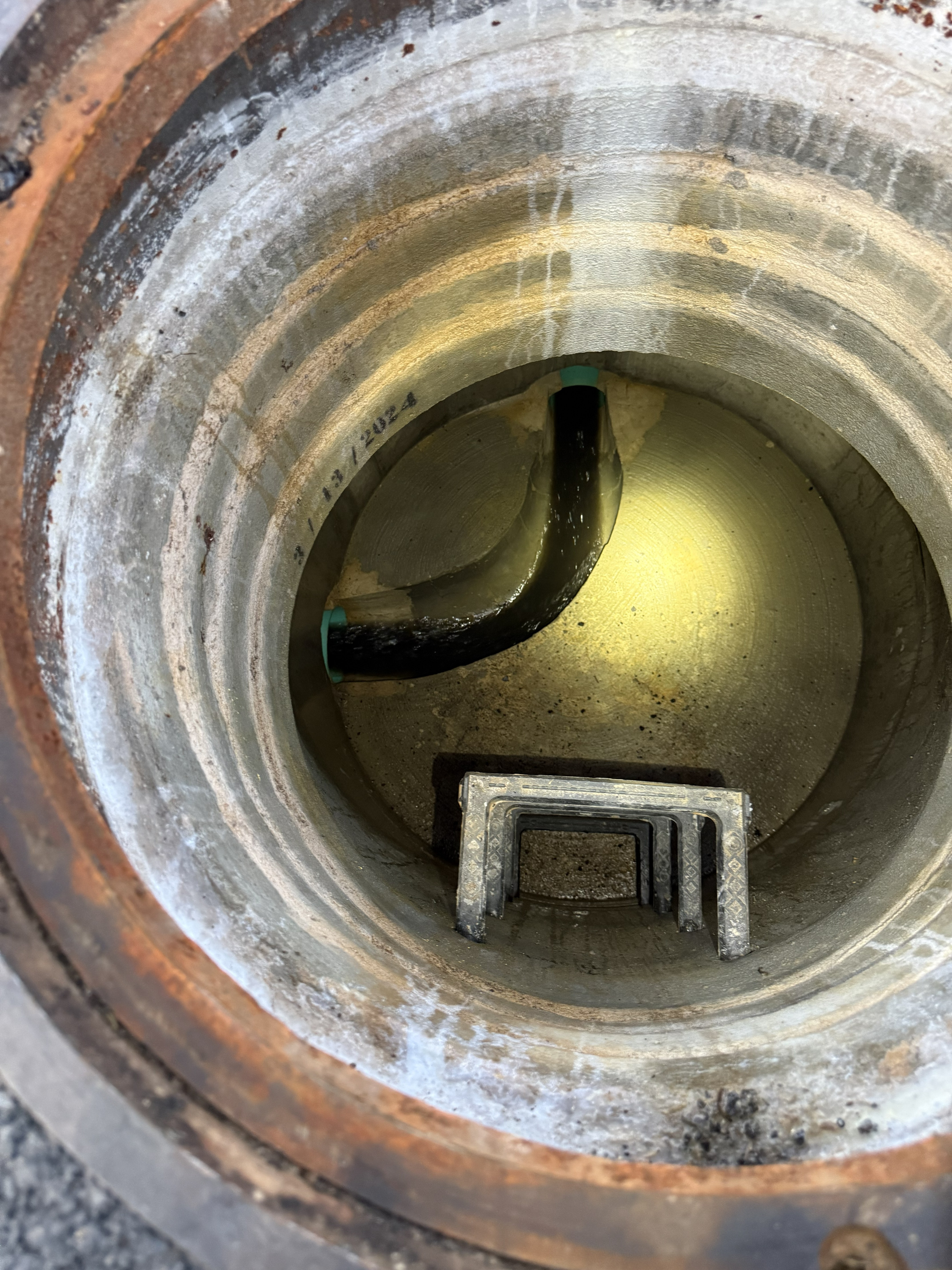 Lift station wet well opened — submersible pumps visible with yellow rope guides