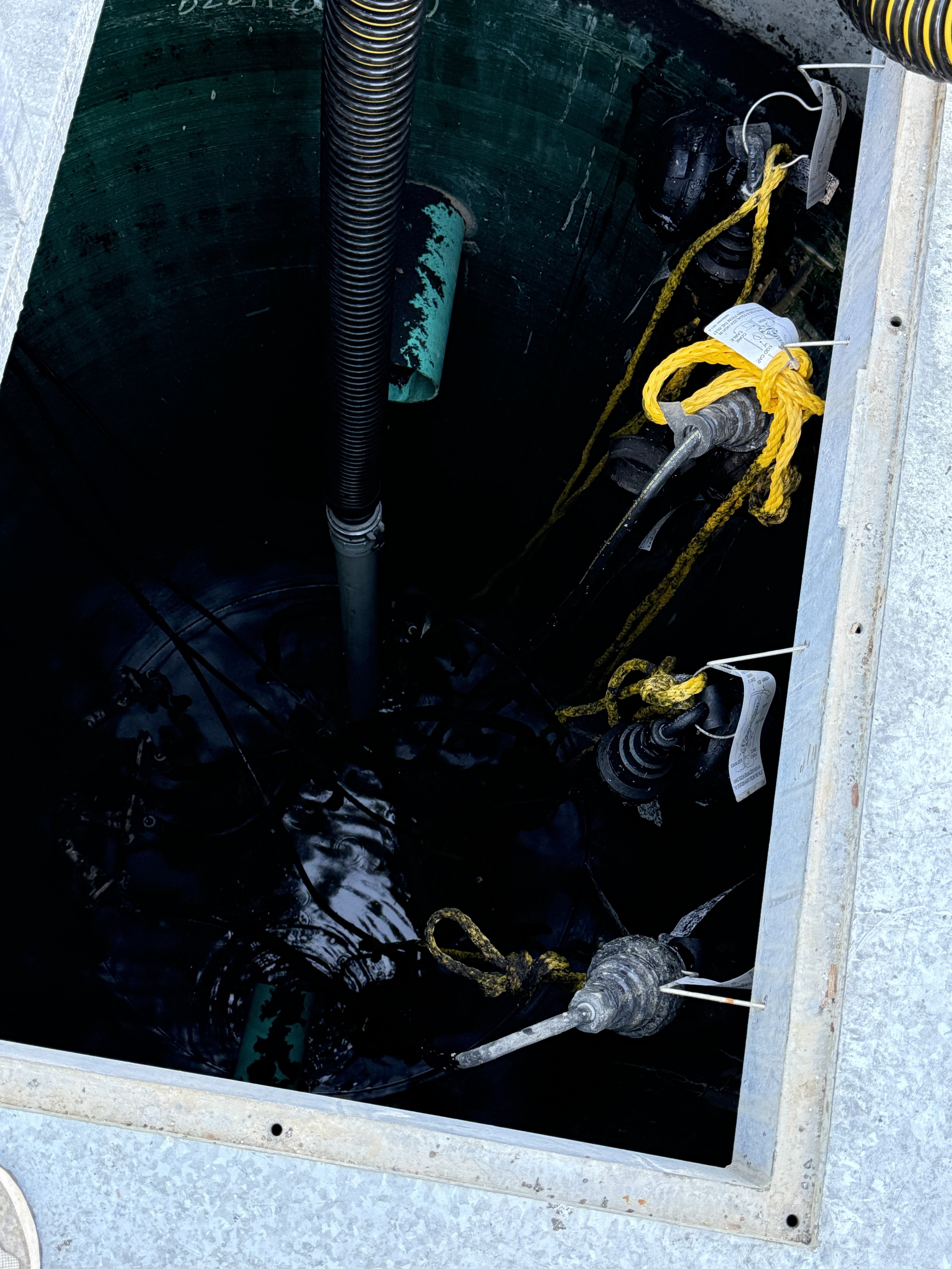 Lift station interior during vacuum truck cleaning — pumps and floats exposed