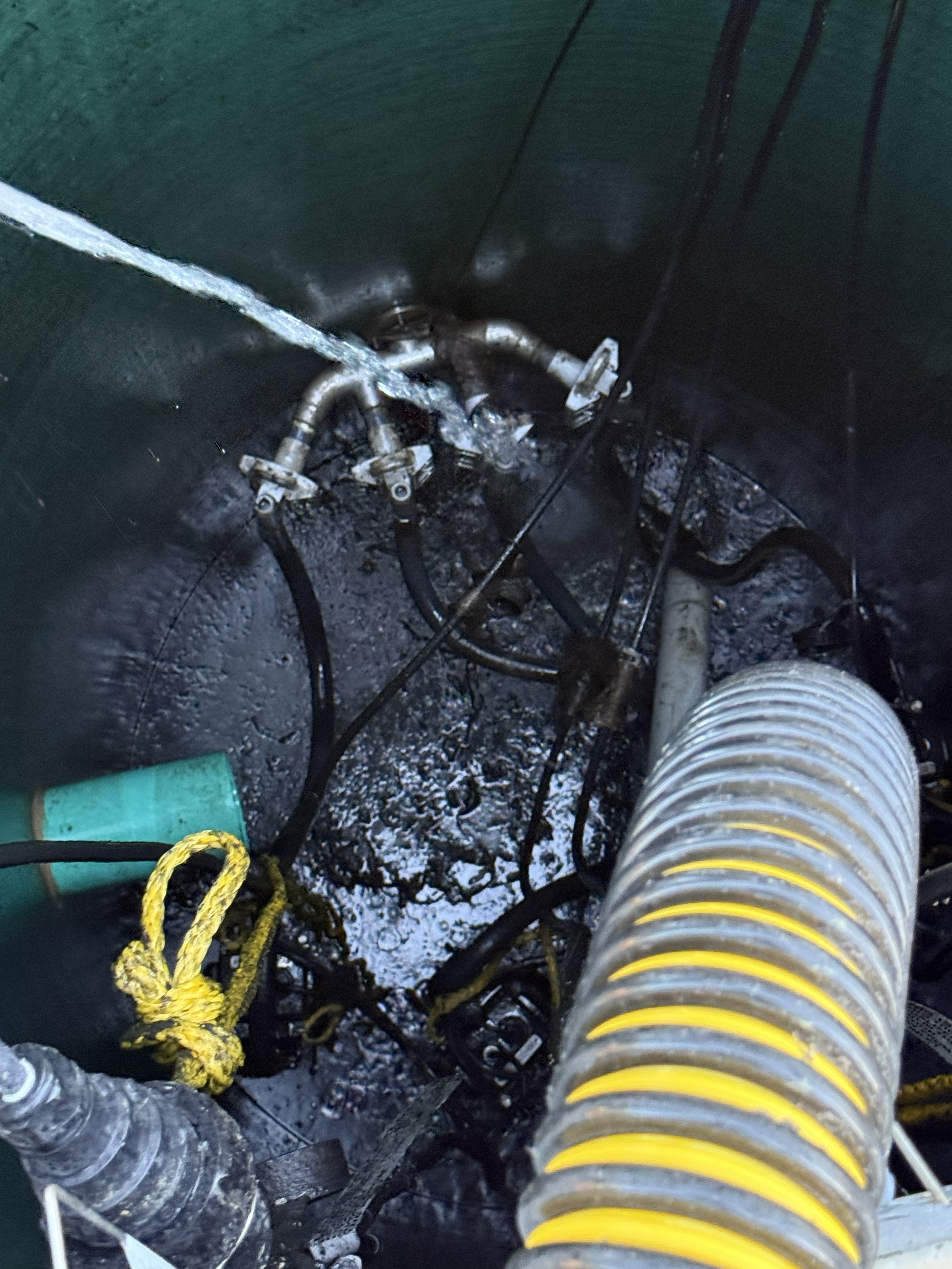 Vacuum truck hose inserted into lift station — removing accumulated debris